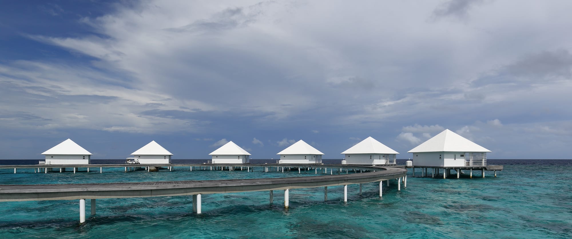 Overwater villas on stilts above a clear turquoise lagoon in the Maldives